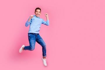 Full body photo of cute teen boy jumping winning dressed stylish blue clothes isolated on pink color background