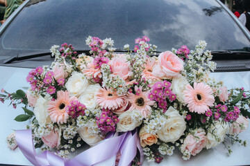 Bouquet of white flowers on the hood of a bride's wedding car, wedding decoration of a car from a...