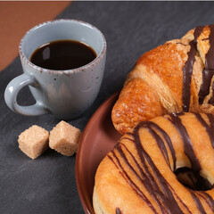 Vassoio con tazzina di caffè e piatto con cornetto e ciambella al cioccolato