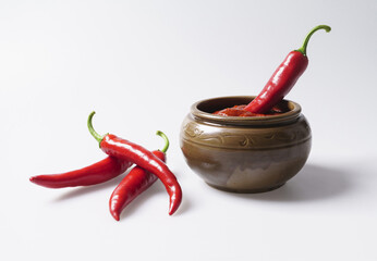 Close-up of three raw red peppers on white floor with one in red pepper paste on a jar, South Korea
