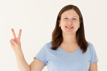 Young caucasian smiling happy friendly woman in stylish casual blue t-shirt show victory v-sign gesture isolated on white background studio portrait People lifestyle concept