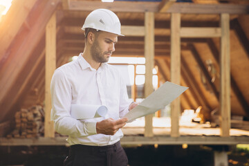 Architect wooden buildings. Man stands under frame wooden house. Man architect studies...