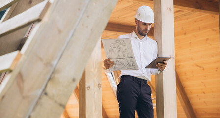 Man builder. Foreman studies blueprints with tablet. Construction company. Architect in unfinished...