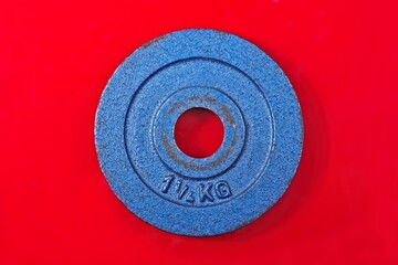 Blue Barbell Weight for sport isolated on red background. Horizontal image.