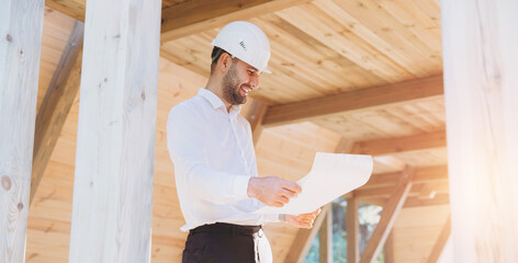 Construction engineer in white helmet. Developer with construction documentation on the background...