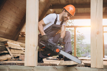 Man worker in work uniform and gloves working with chainsaw of woodcutter sawing chain saw in...