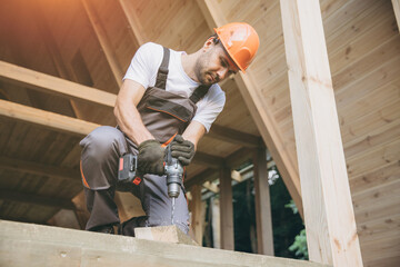 Construction worker working with screwdriver on wooden frame, diy eco-friendly homes concept. Man...