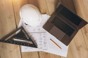 Top view mock -up architectural office desk with copy space, wooden floor with laptop, white helmet construction, pencil, ruler and paper roll, copy space, mock up