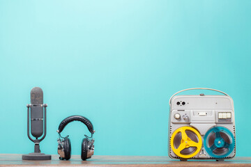 Retro microphone, radio and reel-to-reel audio tape recorder on the wooden table front mint blue...