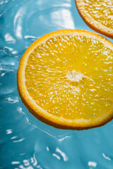 Orange slices floating on rippling water, creating a vibrant contrast of blue and orange hues