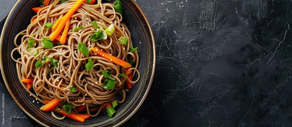 Aufkleber Close up of a bowl of soba noodles with carrots and scallions on a black background suitable for adding text with copy space image