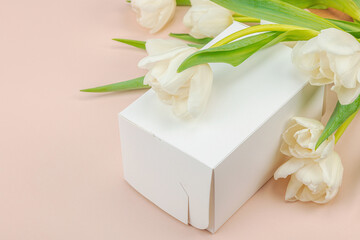 Gift concept. Wrapped surprise box, white tulips on apricot background