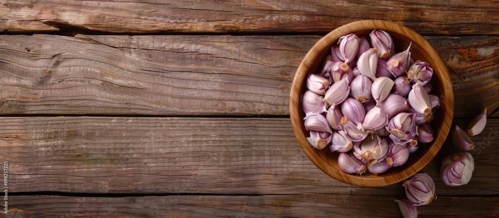 Poster a bowl filled with garlic and onion on a wooden surface with copy space image available