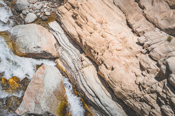 Texture of stone rocks of rock in Tien Shan mountains in Pamir, stream flows between rocks, landscape with rocks for background