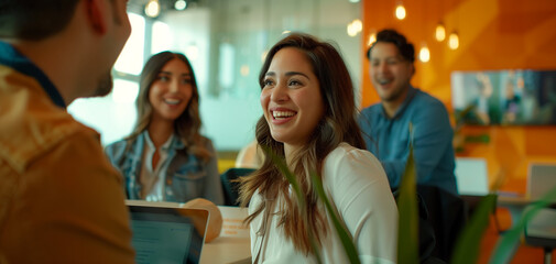 A group of young professionals in an office setting were gathered around one person who was presenting on their tablet to another individual sitting down and smiling at them