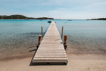 Fototapeta premium A wooden jetty stretches out into the turquoise Mediterranean sea at Rondinara beach on the island of Corsica