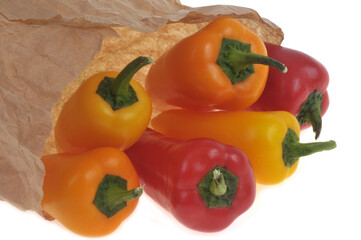 Mini poivrons rouges et jaunes sortant d'un sac en papier en gros plan sur fond blanc