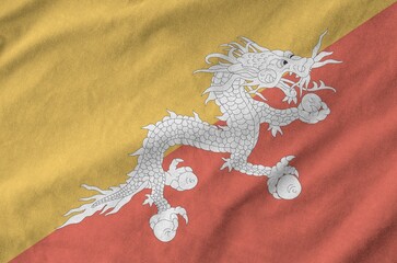 Bhutan flag depicted on folded wavy fabric of old cloth close up