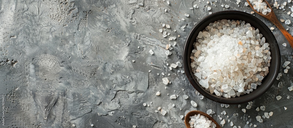 Poster Top down view of mineral bath salt on a grey background with ample copy space for text or images