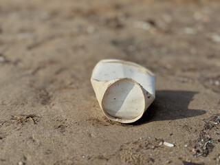 A paper cups is laying on the sand