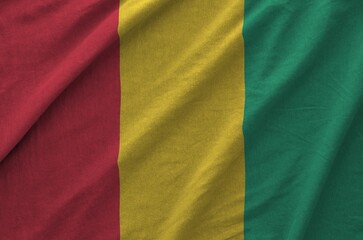 Guinea flag depicted on folded wavy fabric of old cloth close up