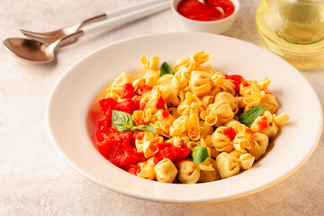 Sacсhettini pasta in a plate with tomato sauce.