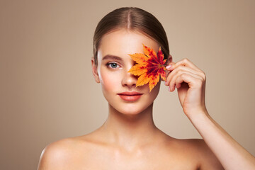 Portrait of beautiful young woman with autumn leafs. Healthy clean fresh skin natural make up beauty eyes