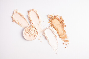 Samples of compact powder and loose powder of different tones, strokes, blocks on a white background. top view. texture of various powders. layout.