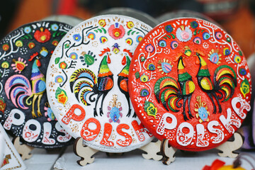Traditional multi-colored souvenir ceramic plates on the stands at local souvenir shop under the open sky in Poland, Krakow.