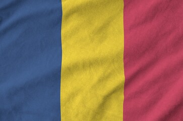 Chad flag depicted on folded wavy fabric of old cloth close up