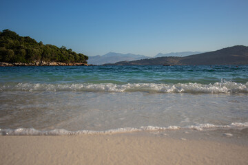 Morning Scenery of Sandy Shore with Ionian Sea and Ksamil Island in Southern Albania. Albanian Landscape of Water and Mountains during Summer Morning.