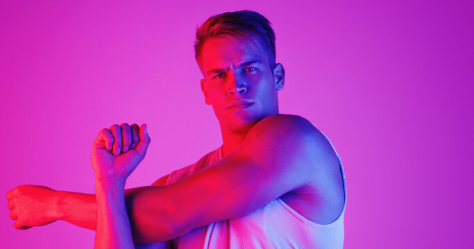 Portrait, fitness and man stretching arm for health or wellness isolated on neon background in studio. Face, sport athlete or warm up muscle to get ready for exercise, workout or flexibility training