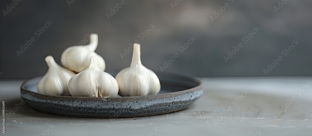 Sticker Allium sativum also known as single clove garlic pearl garlic or solo garlic displayed on a small plate with selective focus in a copy space image