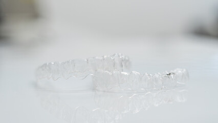 A dentist's gloved hands holding clear dental retainers. Ideal for dental care promotions, orthodontic education, and health-related content.