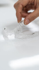A dentist's gloved hands holding clear dental retainers. Ideal for dental care promotions, orthodontic education, and health-related content.