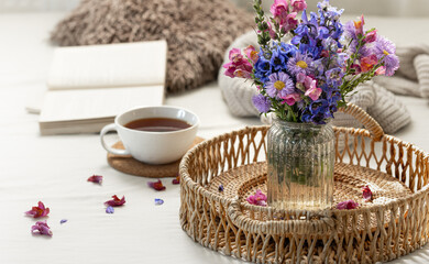 Cup of tea, a bouquet of wildflowers, book and knitted element.
