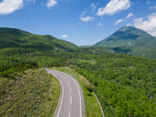 Rausu, Hokkaido: Aerial view of the Shiretoko pass road with the Mt Rausu volcano in the Shiretoko peninsula between Utoro and Rausu town on a sunny summer day in Japan.