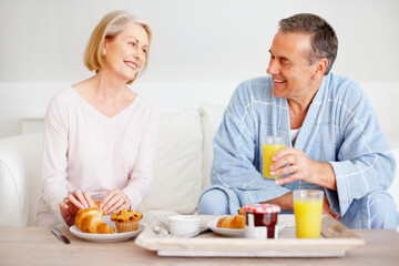 Mature couple, happy and breakfast together on sofa with bonding, diet nutrition and support in home. Smile, man and woman with morning meal, healthy food and romantic time for love relationship