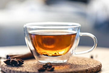 Close-up, glass cup of aromatic black tea on a blurred background.