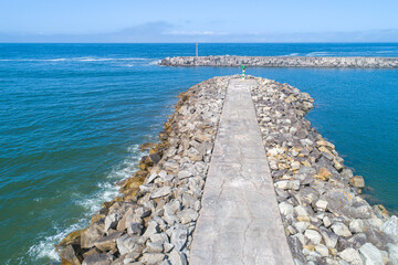 Fototapeta premium view of the breakwater of a harbor on a summer day with calm seas
