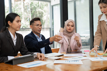 Group of Asian business men and women sitting and looking at documents at the office.