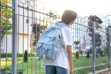 Schoolgirl with a backpack on her shoulders. School on the background of the sunset. Back to school.