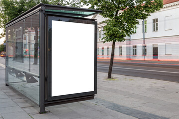 Blank White Bus Stop Vertical Poster Billboard Mockup On An Empty City Street. Advertising Lightbox On The Sidewalk With Car Light Trails In The Background