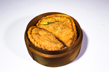 two traditional Indonesian fried foods, served on a bamboo basket and garnished with chilies
