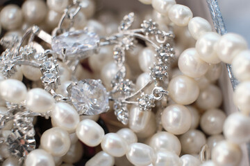 A mix of pearl strands and silver diamond jewelry is displayed, highlighting the detailed craftsmanship. The photo emphasizes the luxurious appeal and timeless beauty of classic jewelry pieces.
