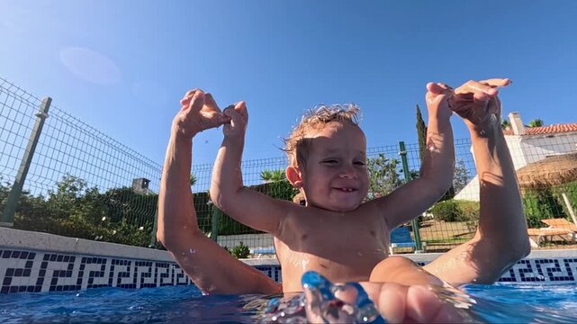 A boy of about two years old playing with his mother in the pool in slow motion