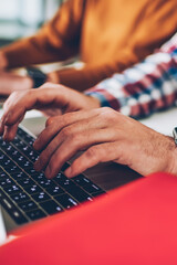 Cropped photo of male's hands keyboarding message in social networks connected to 4g internet, skilled hipster guy creating publication for own website using browser during working with colleague