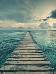 Fototapeta premium Peaceful wooden dock at sunset with ocean and sky backdrop.