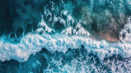 Aerial view of ocean waves breaking, creating a turquoise and white abstract pattern.