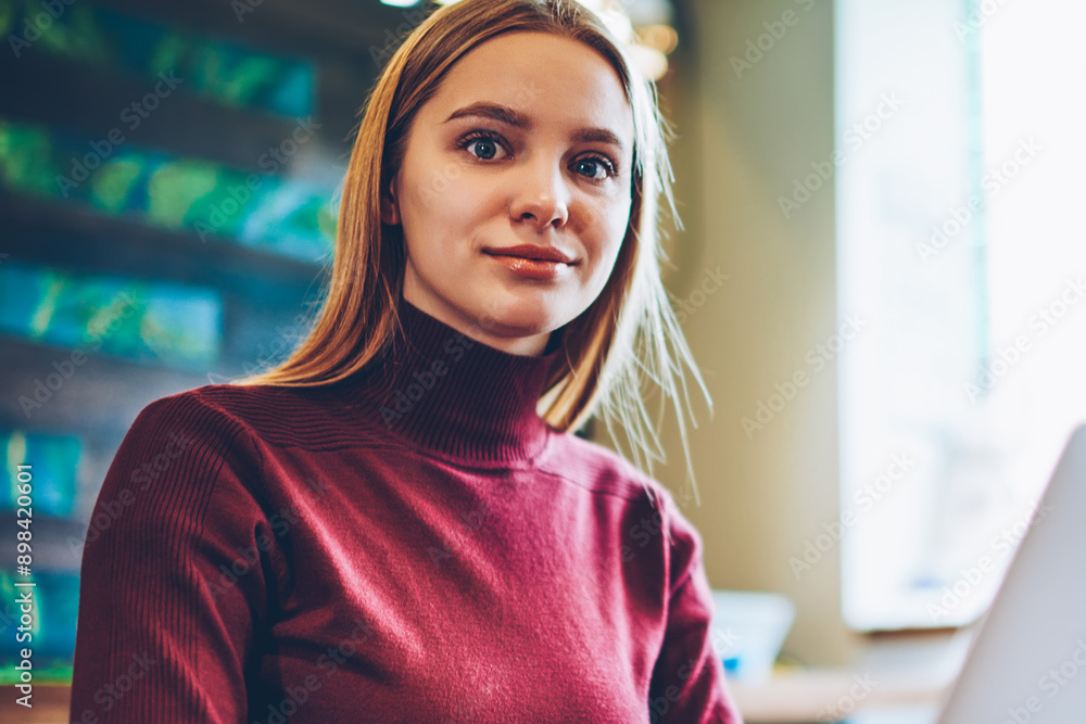 Poster portrait of skilled female student sitting in cafeteria with modern computer on table, caucasian hip